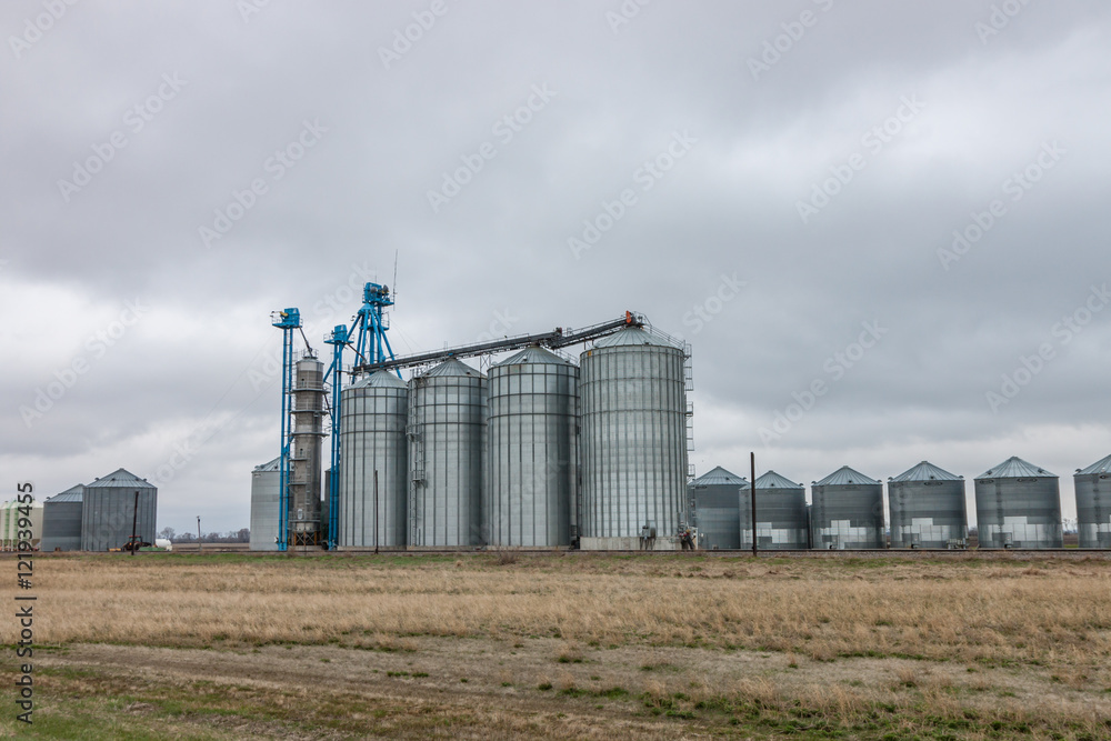 Modern Grain Bins Against Cloudy Sky Modern Grain Bins Against Cloudy Sky
