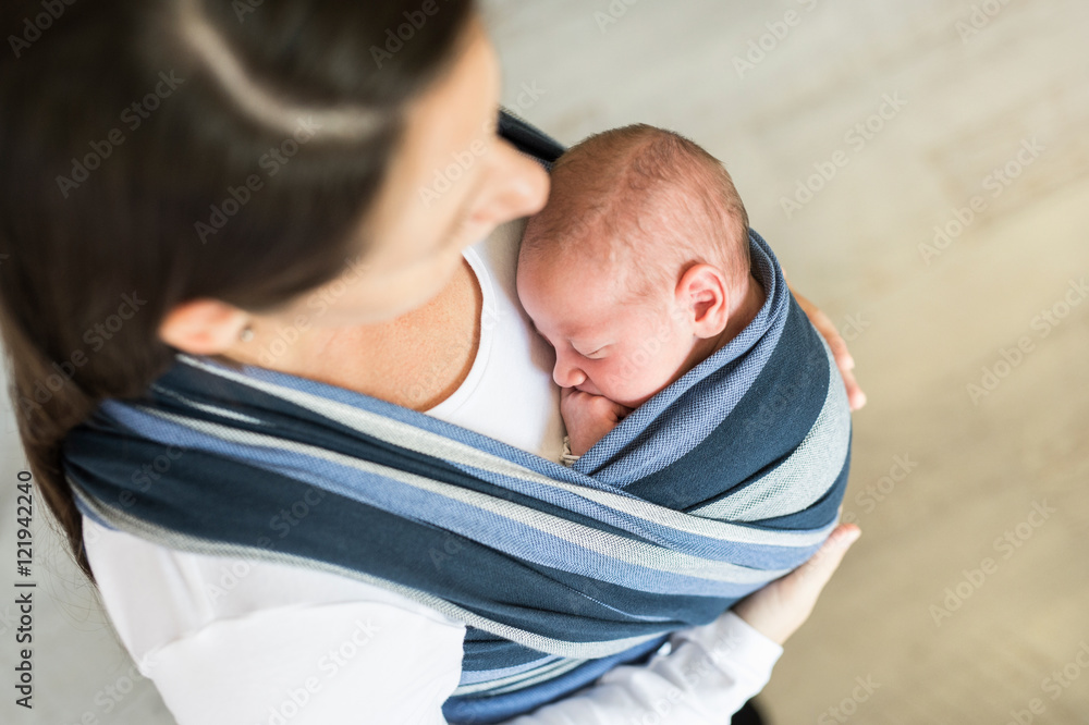 Unrecognizable young mother with her son in sling Unrecognizable young mother with her son in sling