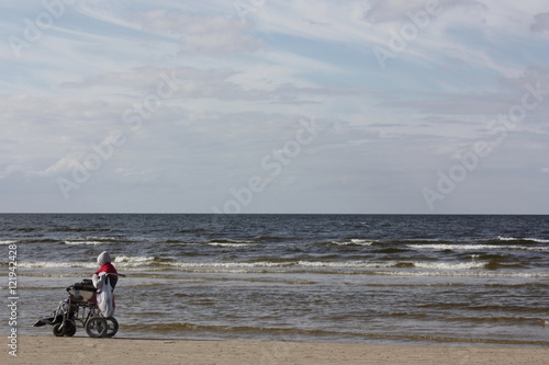 Человек в инвалидной коляске на берегу моря.