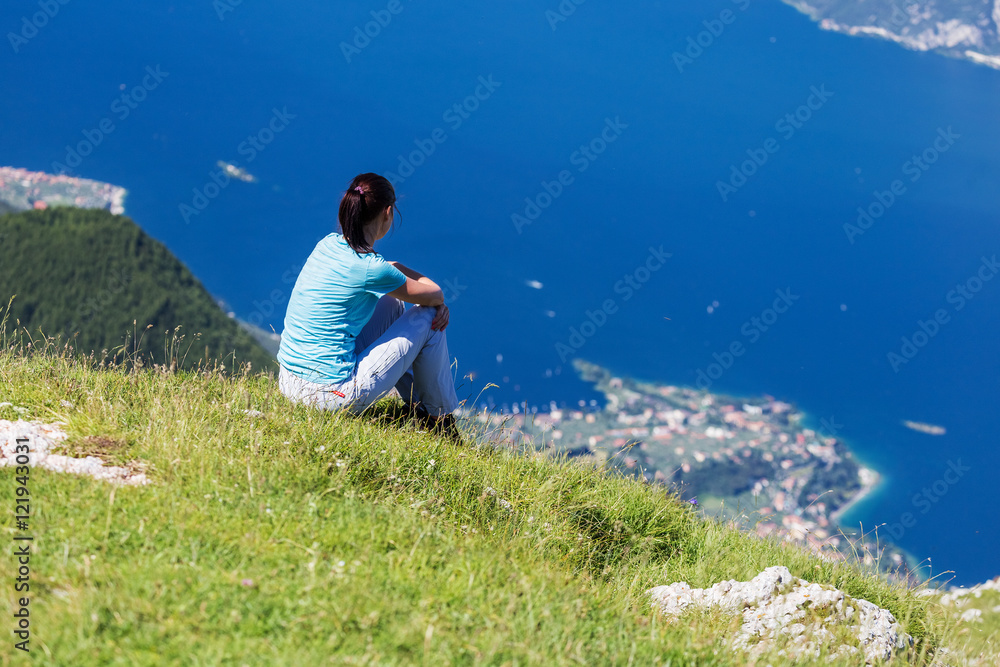 Woman sits on hill above the town on the lake and watching the n