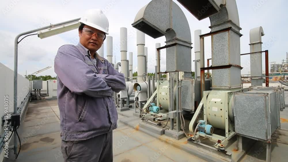 Engineer standing in refinery industrial plant with air blower pipe line at behind Engineer standing in refinery industrial plant with air blower pipe line at behind