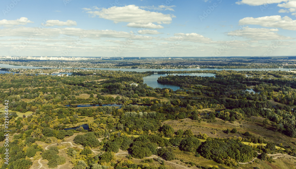 Fototapeta premium Panoramic view of the Kiev suburb from above. Aerial view. Outdoor. Beautiful photos of nature with fields river and reservoirs with high-rise buildings in the background.