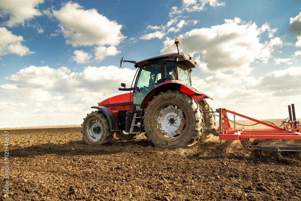 Obraz premium Farmer in tractor preparing land with seedbed cultivator