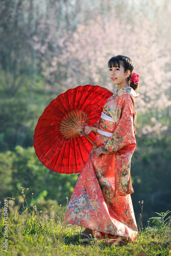Attractive asian woman wearing traditional Japanese Kimono with red umbrella