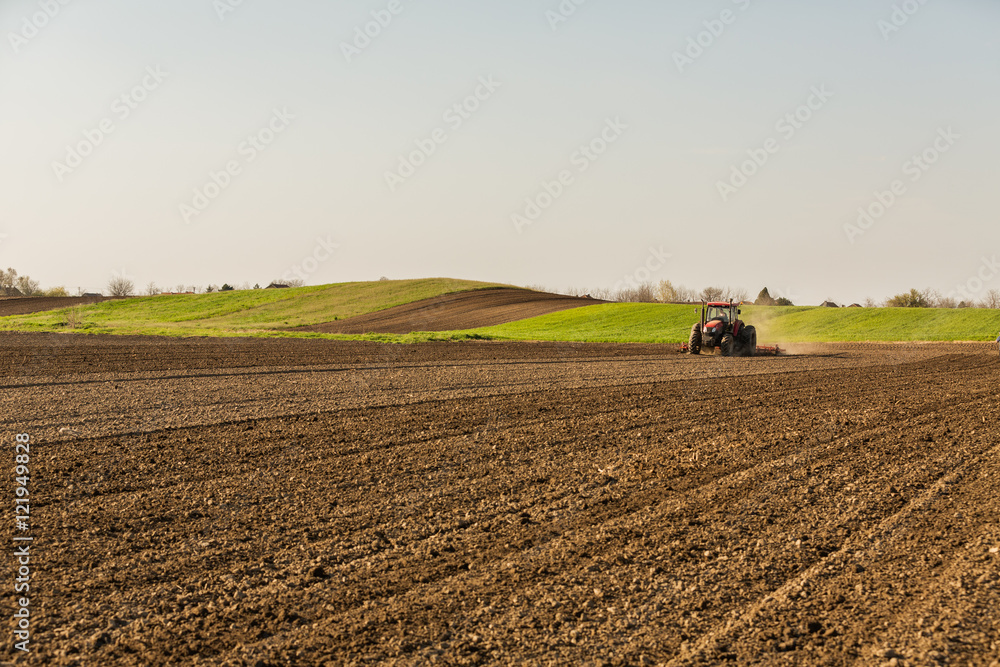Farmer in tractor preparing land with seedbed cultivator