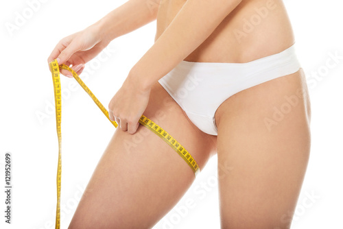 Slim woman measuring her thigh.