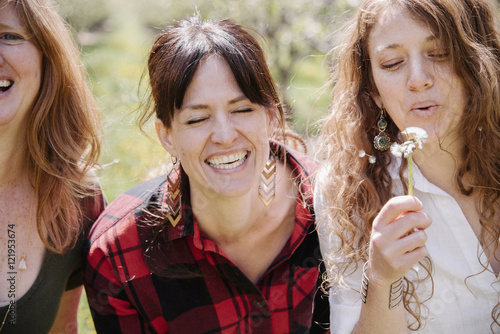 Three friends, women on a sunny day holding dandelion closk.  photo