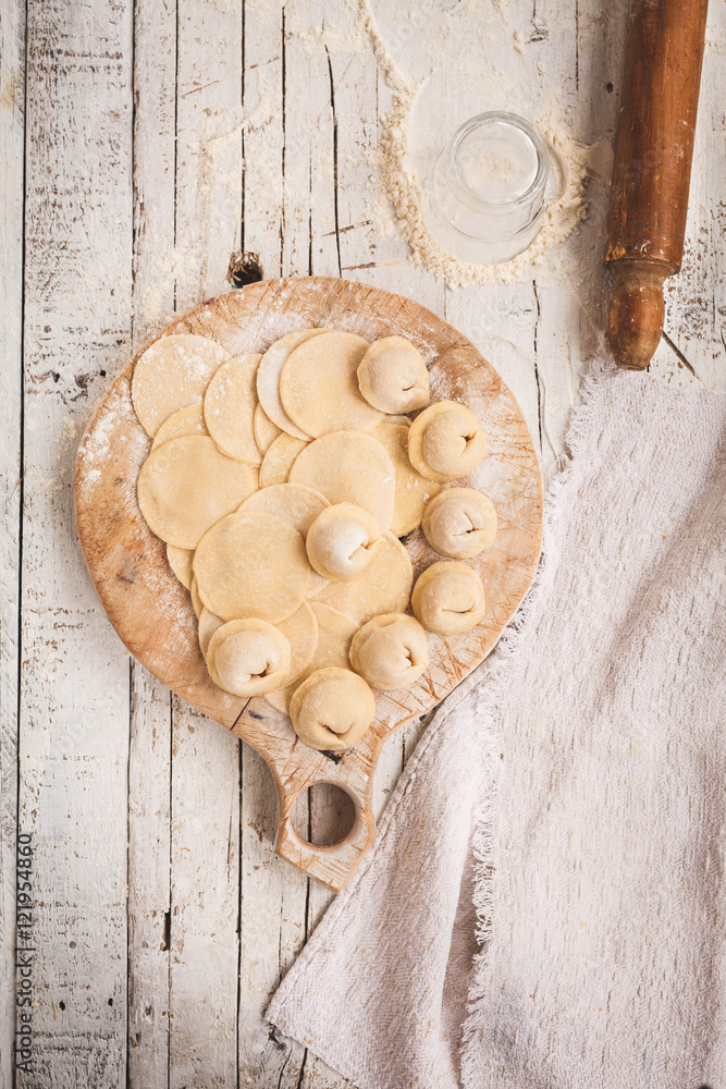 Sculpt pierogy concept. Include rustic round cutting board with pieces of dough, making pierogies and dough ball with rolling pin Sculpt pierogy concept. Include rustic round cutting board with pieces of dough, making pierogies and dough ball with rolling pin