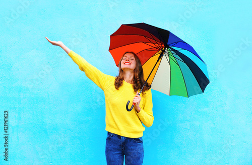 Happy smiling young woman holding colorful umbrella in autumn da