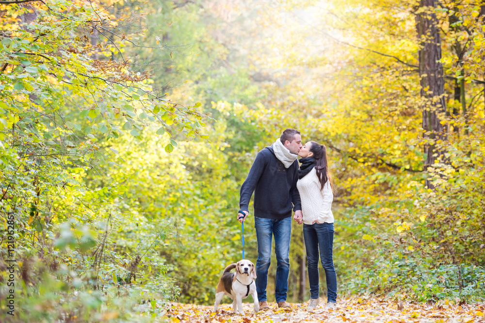 Young couple with dog on a walk in autumn forest