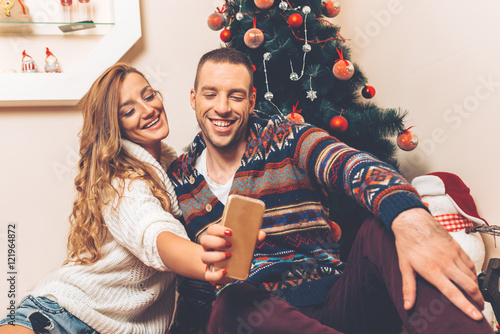 Young couple under christmas tree having fun. photo