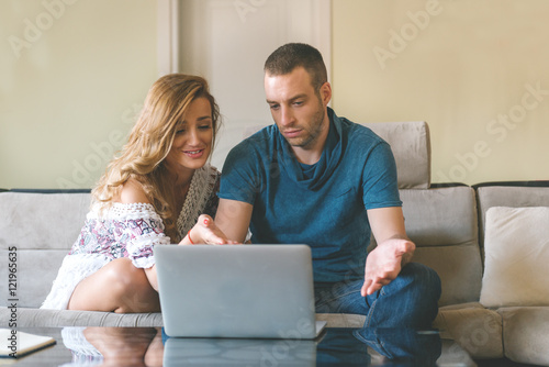 Young smiling couple working at home  with laptop and smartphone.