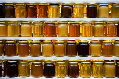 Jars of different honey varieties stocked on a shelf photo