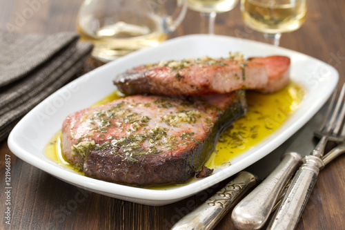 Fotografie fried tuna with sauce on white dish on wooden background
