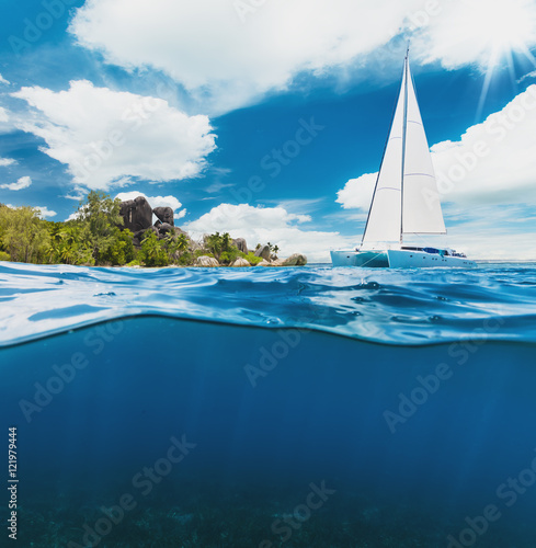 Catamaran boat sailing next to tropical island