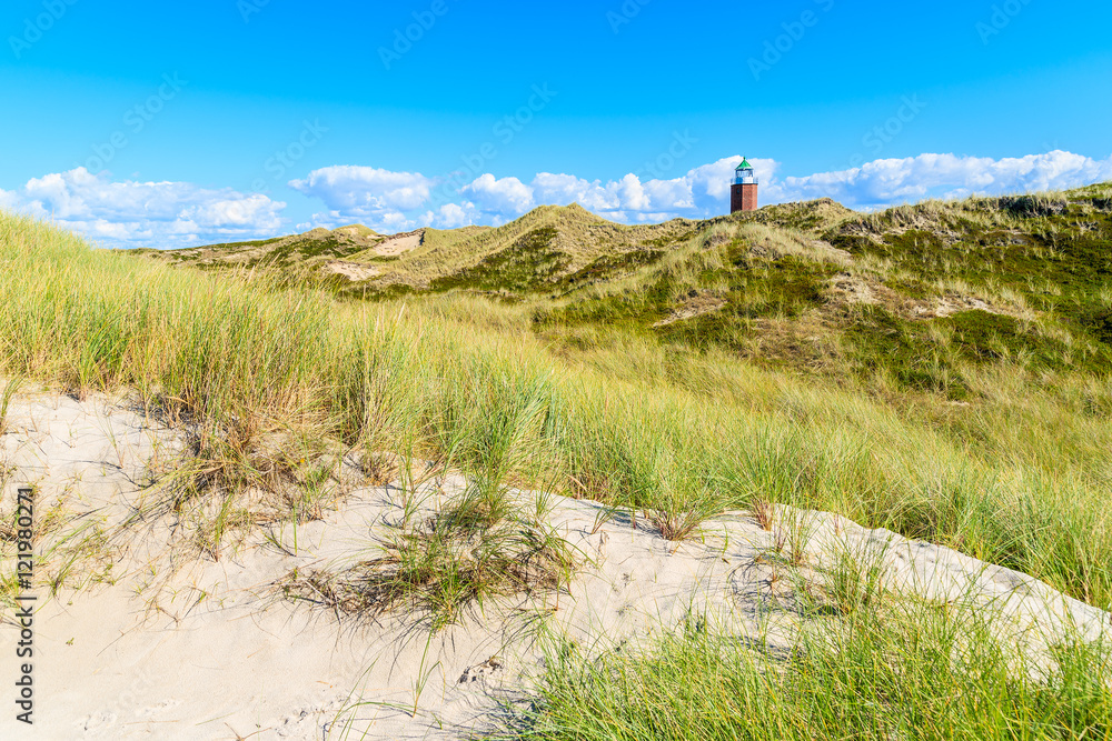Lighthouse on sand dune against blue sky with white clouds on northern coast of Sylt island near Kampen village, Germany