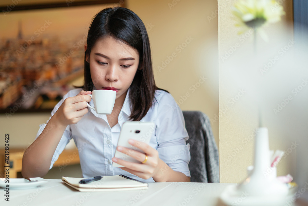 Young woman using smartphone with a coffee cup and notebook. Young woman using smartphone with a coffee cup and notebook.