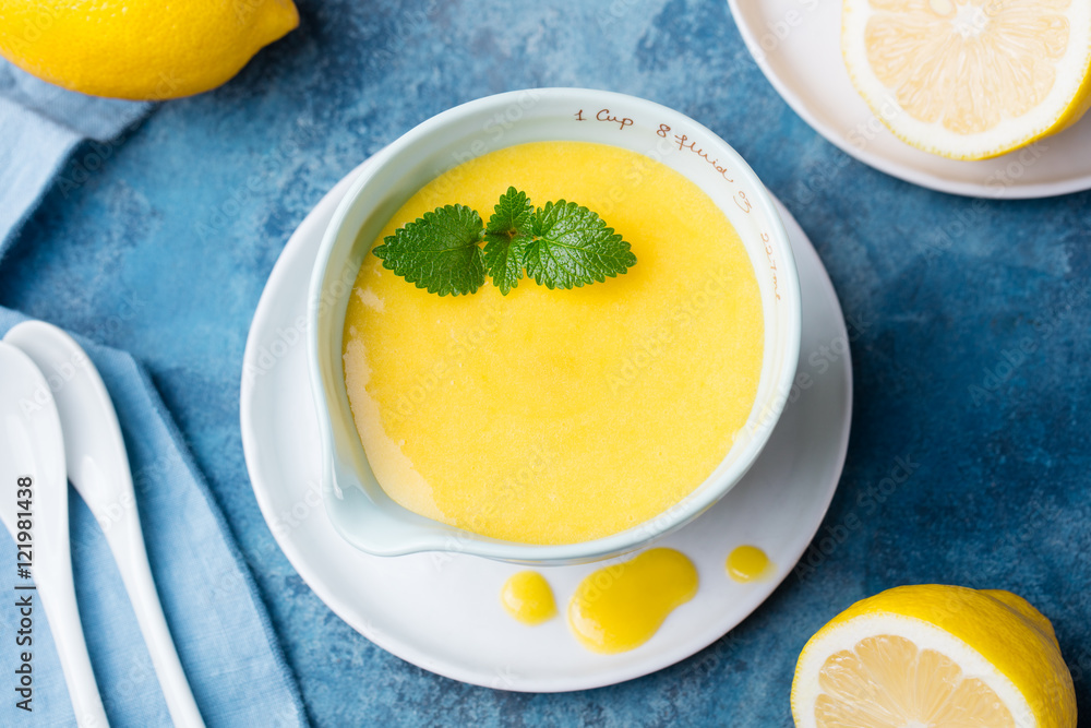 Lemon curd in ceramic bowl with fresh lemons on a blue napkin background. Top view. Selective focus Lemon curd in ceramic bowl with fresh lemons on a blue napkin background. Top view. Selective focus