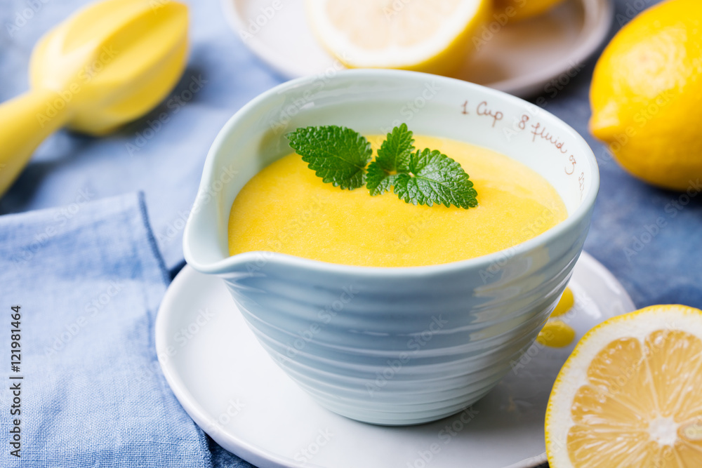 Lemon curd in ceramic bowl with fresh lemons on a blue napkin background. Selective focus Lemon curd in ceramic bowl with fresh lemons on a blue napkin background. Selective focus