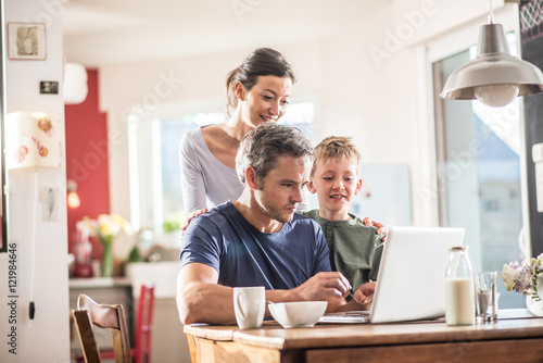 A family using a laptop while having breakfast in the kitchen