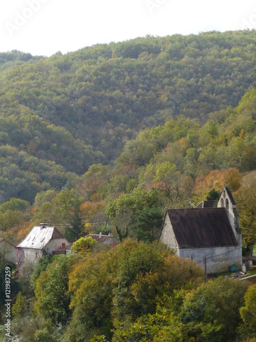 Chapel and house nestling in a wooded valley in the Dordogne region of France with the foliage of the scrub oak starting to take on autumn colouring