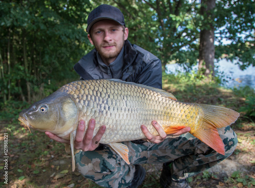 Happy angler with carp fishing trophy.