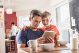 A father and son using a tablet while having breakfast
