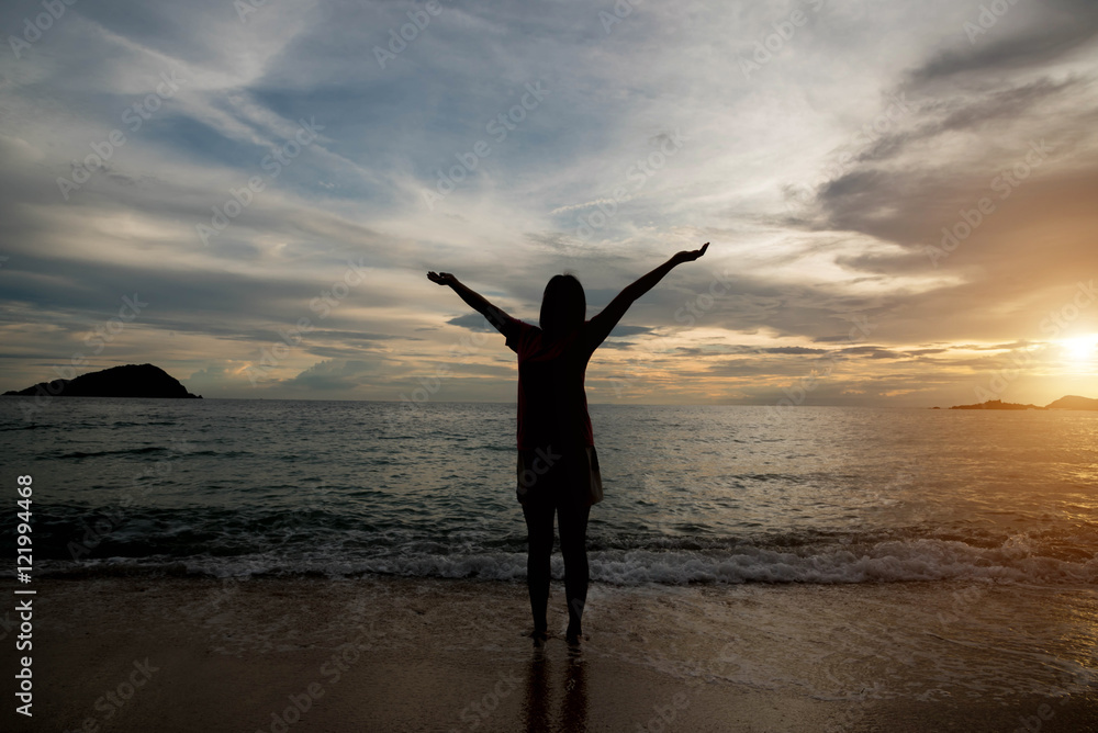 Woman silhouette on the beach at sunrise