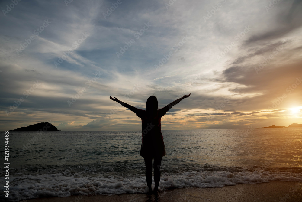 Woman silhouette on the beach at sunrise