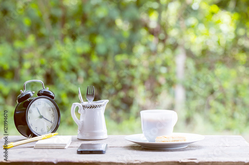 Coffee cup with sweets on the table with brown paper notes with a pen nearby. In the background is bokeh