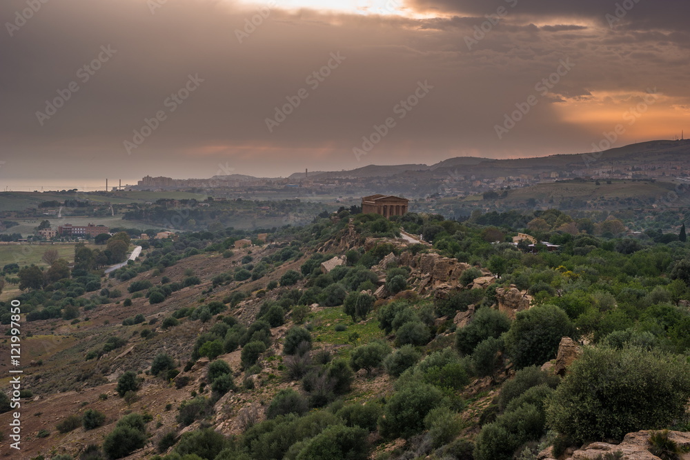 Sunset in Valley of temples in Agrigento in Sicily with clouds and night illumination.