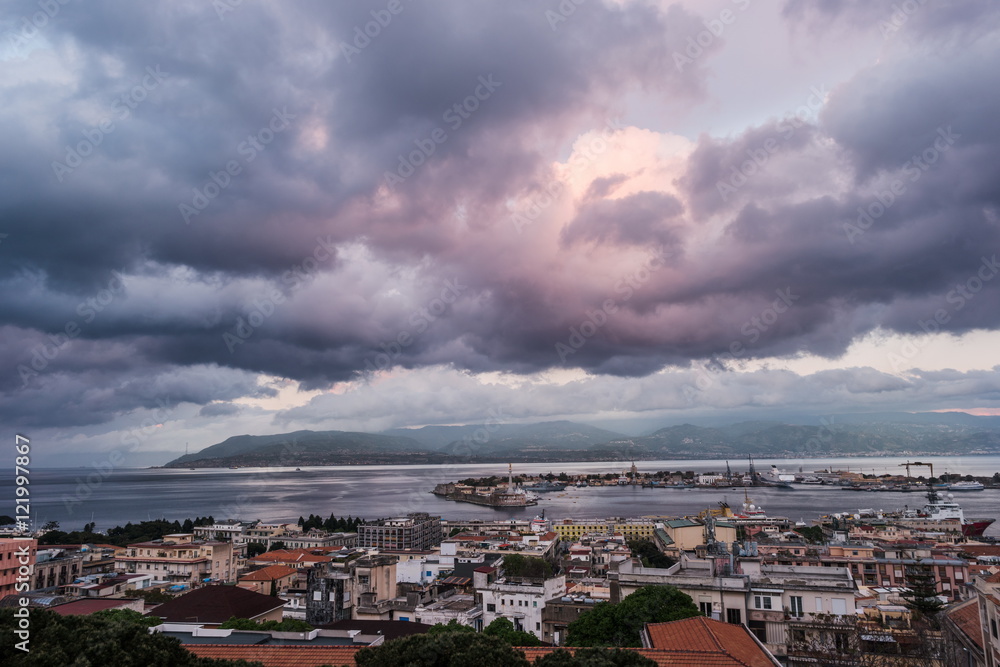Sunset in the Port of Messina in Sicily Italy. Clouds and sunset light with night illumination.