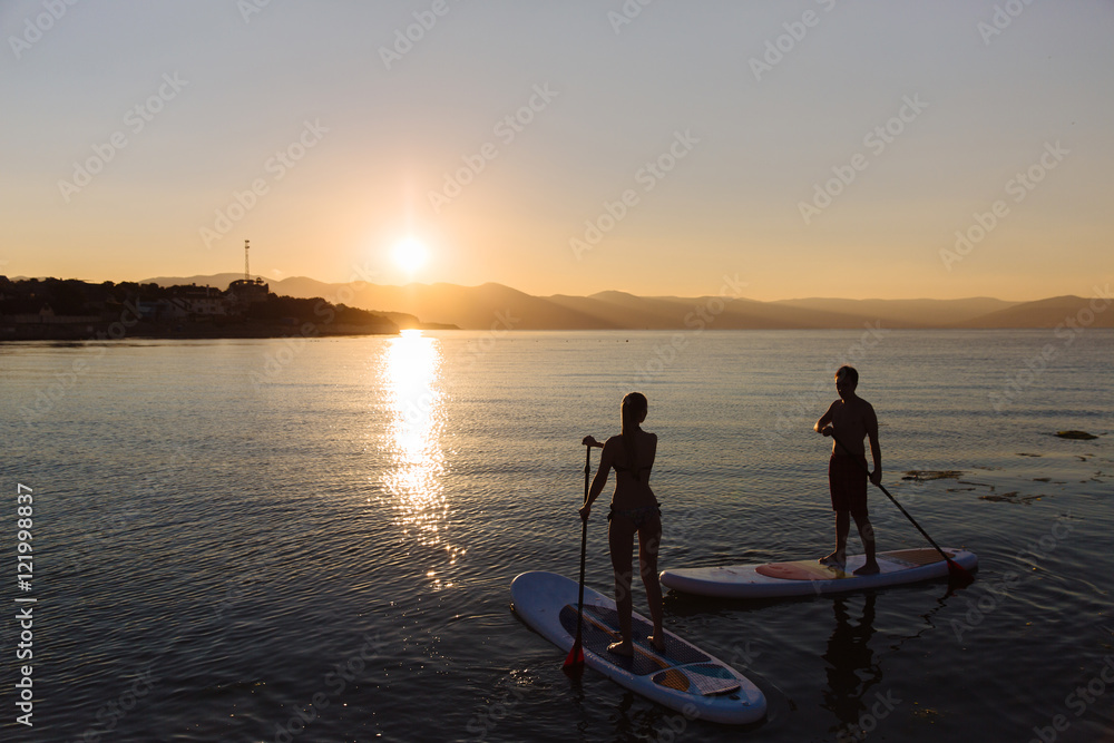 Silhouette of male and female on sup surf swimming at the ocean. Concept lifestyle, sport, love