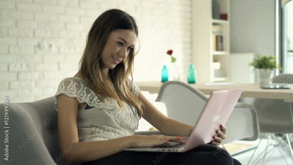 Young, pretty woman using laptop sitting on sofa at home
Young, pretty woman using laptop sitting on sofa at home
