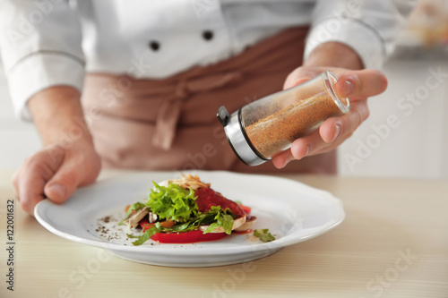 Fototapeta Naklejka Na Ścianę i Meble -  Chef cook adding pepper to dish, closeup