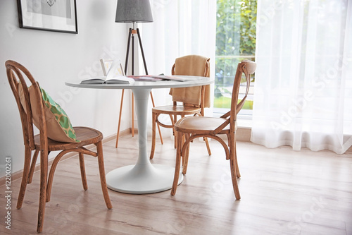 Modern white table and wooden chairs near window