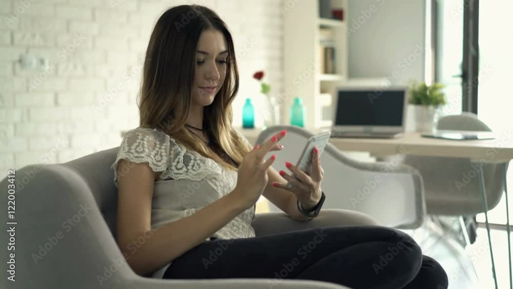 Young, pretty woman using smartphone sitting on sofa at home
Young, pretty woman using smartphone sitting on sofa at home