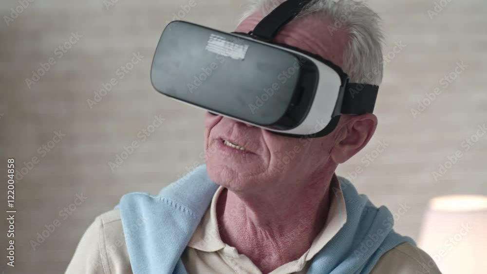 Slow motion of elderly man in virtual reality headset gesturing and trying to touch something Slow motion of elderly man in virtual reality headset gesturing and trying to touch something
