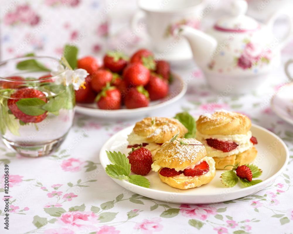 Cream puff cakes or profiterole filled with whipped cream, served with strawberries Cream puff cakes or profiterole filled with whipped cream, served with strawberries
