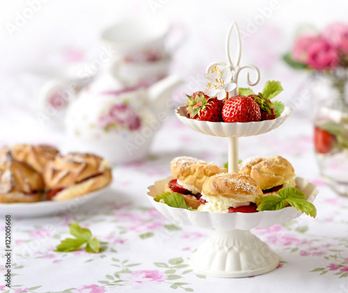 Cream puffs cakes or profiterole filled with whipped cream served with strawberries in plateau
