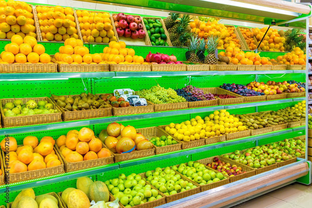 Shelf with fresh organic fruits on a farm market supermarket. Apple, orange, grapes, persimmon, kiwi, pineapple, pear, plum, prunes, melon, watermelon, exotic fruit.