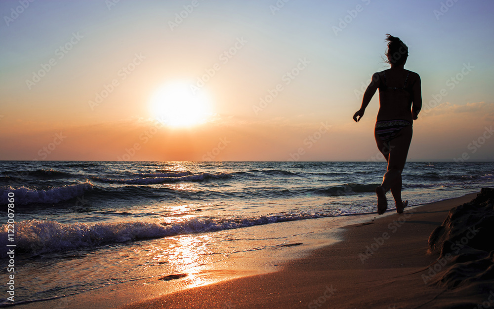 Girl running on beach at sunset