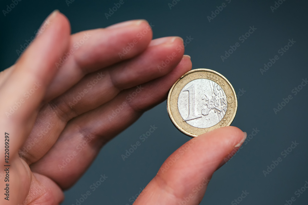 Business woman holding one euro coin between fingers Business woman holding one euro coin between fingers
