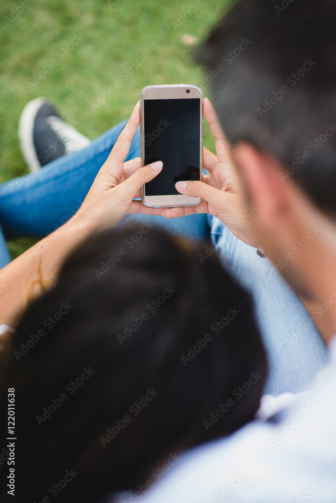 Young couple using smartphone together. Detail of man and woman holding cellphone.