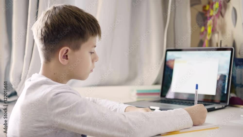 A boy sits at the table in his room and wrote homework. 4K video A boy sits at the table in his room and wrote homework. 4K video