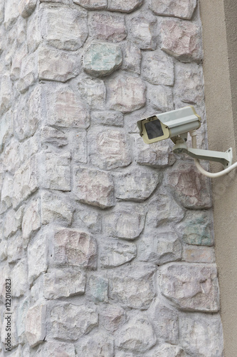 The CCTV security camera operating on stone brick wall.