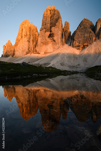 Famous mountain peaks of Tre Cime and their reflection on a still lake at sunset. Amazing Landscape of Dolomites range. Fantastic hike. Peaceful feeling.