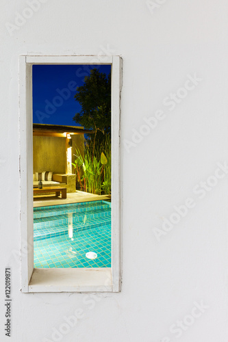 White wall window with swimming pool view. © mikumistock