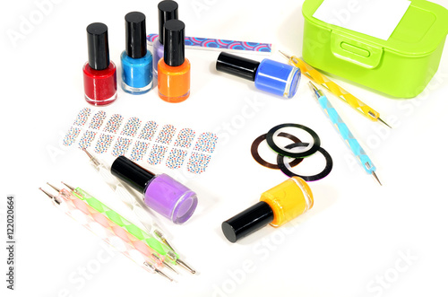 Table full of manicure ustensils, coloured nail polish,nail decals stickers, striping tape, nail file, dotting nail pens, vinyl sheets. Nails art accesories isolated on white. 