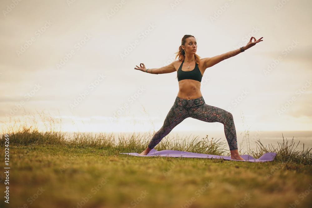 Fit young woman doing yoga on cliff